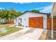 Charming single-story home with a wooden garage door, manicured lawn, and white exterior at 208 Palmetto W Rd, Nokomis, FL 34275