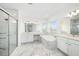 Spacious bathroom with marble tile, a glass shower, and soaking tub, creating a luxurious spa-like experience at 2492 Overfalls Pl, Wesley Chapel, FL 33543
