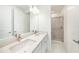 Well-lit bathroom with double sinks and a glass-enclosed shower boasting white cabinets and modern fixtures at 2492 Overfalls Pl, Wesley Chapel, FL 33543