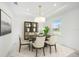 Bright dining room with modern light fixture, decorative shelving, and large window overlooking the neighborhood at 2492 Overfalls Pl, Wesley Chapel, FL 33543