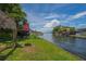 View of the serene canal from the lush backyard with a glimpse of the property's exterior at 33 Cypress Dr, Palm Harbor, FL 34684