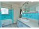 Bright blue-tiled bathroom with a bathtub, shower, and a large mirror at 33 Cypress Dr, Palm Harbor, FL 34684