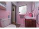 This unique bathroom features pink tiling, a vintage sink, and a modern toilet at 33 Cypress Dr, Palm Harbor, FL 34684