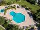 Aerial view of a unique pool area with lounge chairs and tiki huts amid manicured lawns at 400 Island Way # 1606, Clearwater Beach, FL 33767