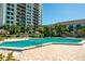 Inviting community pool surrounded by lush landscaping, lounge chairs, and tiki umbrellas at 400 Island Way # 1606, Clearwater Beach, FL 33767