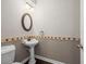 Powder room with pedestal sink, decorative border, and oval mirror at 4521 Cheval Blvd, Lutz, FL 33558