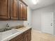 Well-lit laundry room featuring wood cabinets, granite counters, and tile flooring at 4521 Cheval Blvd, Lutz, FL 33558