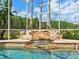 Close-up of pool waterfall feature surrounded by decorative rocks and tropical landscaping creating a tranquil oasis at 4521 Cheval Blvd, Lutz, FL 33558