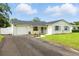 Charming single-story home featuring a brick exterior, blue shutters, manicured lawn and long driveway at 4611 W Bay Court Avenue, Tampa, FL 33611