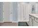 Well-lit bathroom features a walk-in shower with white curtain and grey rug at 5474 Flint Hills Dr, Wimauma, FL 33598