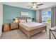 Comfortable bedroom featuring a queen-sized bed, blue accent wall, and ample natural light at 5474 Flint Hills Dr, Wimauma, FL 33598