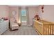 A cozy bedroom featuring a wood crib and arm chair at 5474 Flint Hills Dr, Wimauma, FL 33598