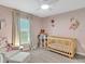 A cute pink Bedroom featuring a wood crib and ceiling fan at 5474 Flint Hills Dr, Wimauma, FL 33598