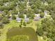 This aerial shot features a charming home with a pool, a large pond, and beautifully landscaped yards in a quiet neighborhood at 1271 Candlelight Blvd, Brooksville, FL 34601
