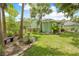 Landscaped backyard featuring a grassy area with a bench, garden, and green exterior at 1271 Candlelight Blvd, Brooksville, FL 34601