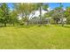 Expansive, green backyard featuring a screened-in porch, mature trees, and lush grass at 1271 Candlelight Blvd, Brooksville, FL 34601