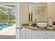 Light bathroom showing a white vessel sink, framed mirror, and doorway to the screened pool area at 1271 Candlelight Blvd, Brooksville, FL 34601