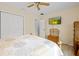Bedroom with ceiling fan, view into the en-suite bathroom, closet, wood floors and TV at 1271 Candlelight Blvd, Brooksville, FL 34601