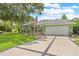 View of the green house with a wide driveway leading to the garage, American flag at 1271 Candlelight Blvd, Brooksville, FL 34601