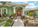 Inviting home entrance with a red door, columns, and decorative landscaping at 1271 Candlelight Blvd, Brooksville, FL 34601