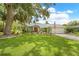Beautiful front lawn with a well-maintained garden and a charming light green single-story home with a red door at 1271 Candlelight Blvd, Brooksville, FL 34601