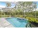 Screened-in pool with patio, water feature, and view of lush backyard with mature trees and a pond at 1271 Candlelight Blvd, Brooksville, FL 34601