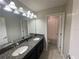 Bathroom features a dual sink vanity with granite countertop, elegant lighting, and opens to the shower at 1596 Ludington Ave, Wesley Chapel, FL 33543
