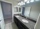 Bathroom features a dual sink vanity with granite countertop, elegant lighting, and opens to more rooms at 1596 Ludington Ave, Wesley Chapel, FL 33543