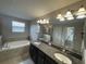 Bathroom featuring double sinks, granite countertops, and a soaking tub at 1596 Ludington Ave, Wesley Chapel, FL 33543