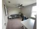 Bedroom features ceiling fan, neutral walls, grey futon, and simple shelving for versatile use at 1596 Ludington Ave, Wesley Chapel, FL 33543