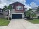 Two story home with a brick red second level, dark garage door and palm trees at 1596 Ludington Ave, Wesley Chapel, FL 33543