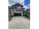 Two story home with a brick red second level, dark garage door and palm trees at 1596 Ludington Ave, Wesley Chapel, FL 33543
