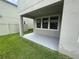 Covered patio with grey painted concrete and view of backyard and three windows at 1596 Ludington Ave, Wesley Chapel, FL 33543