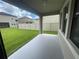Covered patio, white posts, grey concrete with yard view through windows at 1596 Ludington Ave, Wesley Chapel, FL 33543
