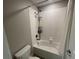 White tiled shower and tub combination featuring shower caddy and bronze fixtures at 1596 Ludington Ave, Wesley Chapel, FL 33543