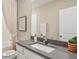 A stylish bathroom featuring gray countertops, a sink, and a framed mirror create a calming and modern space at 17469 Spanish Oak Loop, Land O Lakes, FL 34638