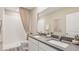 Modern bathroom featuring dual sinks, gray counters, a walk-in shower, and a large mirror at 17477 Spanish Oak Loop, Land O Lakes, FL 34638