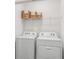 Functional laundry room equipped with modern, white washer and dryer units and overhead shelving at 17477 Spanish Oak Loop, Land O Lakes, FL 34638
