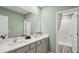 Bathroom features a double sink vanity, framed mirror, and walk in shower at 17491 Spanish Oak Loop, Land O Lakes, FL 34638