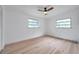 This bedroom features two windows, a ceiling fan, and light wood-look floors at 209 Se Jefferson N Cir, St Petersburg, FL 33702