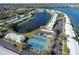 An aerial view of a waterfront community featuring two tennis courts, a pond, and convenient parking at 225 Pompano Se Dr # D, St Petersburg, FL 33705