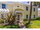 Charming yellow townhouse featuring a well-maintained lawn and decorative palm tree at 225 Pompano Se Dr # D, St Petersburg, FL 33705