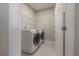 Bright laundry room with tile floors, washer and dryer, and white wire shelving unit at 2469 Stapleford Pl, Wesley Chapel, FL 33543