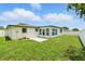 Spacious backyard with lush green grass, white fence, and bright white house with a patio at 3633 Odom Dr, New Port Richey, FL 34652