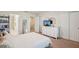 Bright bedroom features white linens, a dresser with TV, and access to an ensuite bathroom at 4935 White Sanderling Ct, Tampa, FL 33619