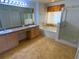Bathroom with a double sink vanity, tub, glass-enclosed shower, and a window for natural light at 5154 Balsam Dr, Land O Lakes, FL 34639