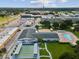 Aerial of community's amenities: shuffleboard, pool, clubhouse, and surrounding shops and lush greenery under a sunny sky at 6015 19Th N St # 117, St Petersburg, FL 33714