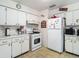 Compact kitchen featuring bright white cabinetry, laminate countertops, and functional appliances at 6832 Treehaven Dr, Spring Hill, FL 34606