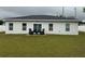 Spacious backyard with freshly cut grass, a patio area with chairs, and a sliding glass door leading inside at 9397 Northcliffe Blvd, Spring Hill, FL 34606
