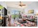 Cozy living room with ceiling fan, wood floors, a large window with blinds, and comfortable seating at 1107 Normandy Trace Rd, Tampa, FL 33602